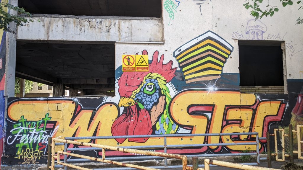 Painting on an abandoned building in Mostar that says Mostar with a rooster.